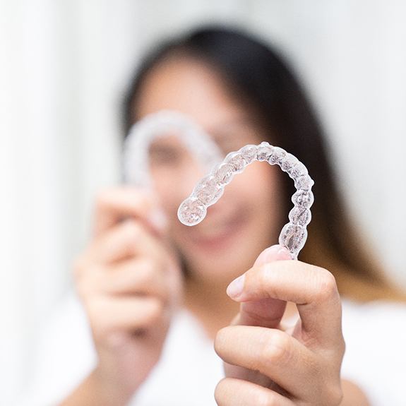 Smiling woman holding clear aligners